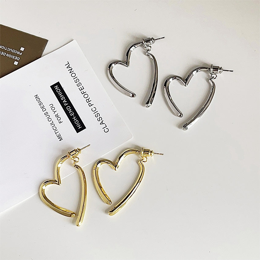 A set of 14K gold-plated and silver-finished heart-shaped stud earrings, showcasing the minimalist design and high-quality brass construction for wholesale jewelry collections.