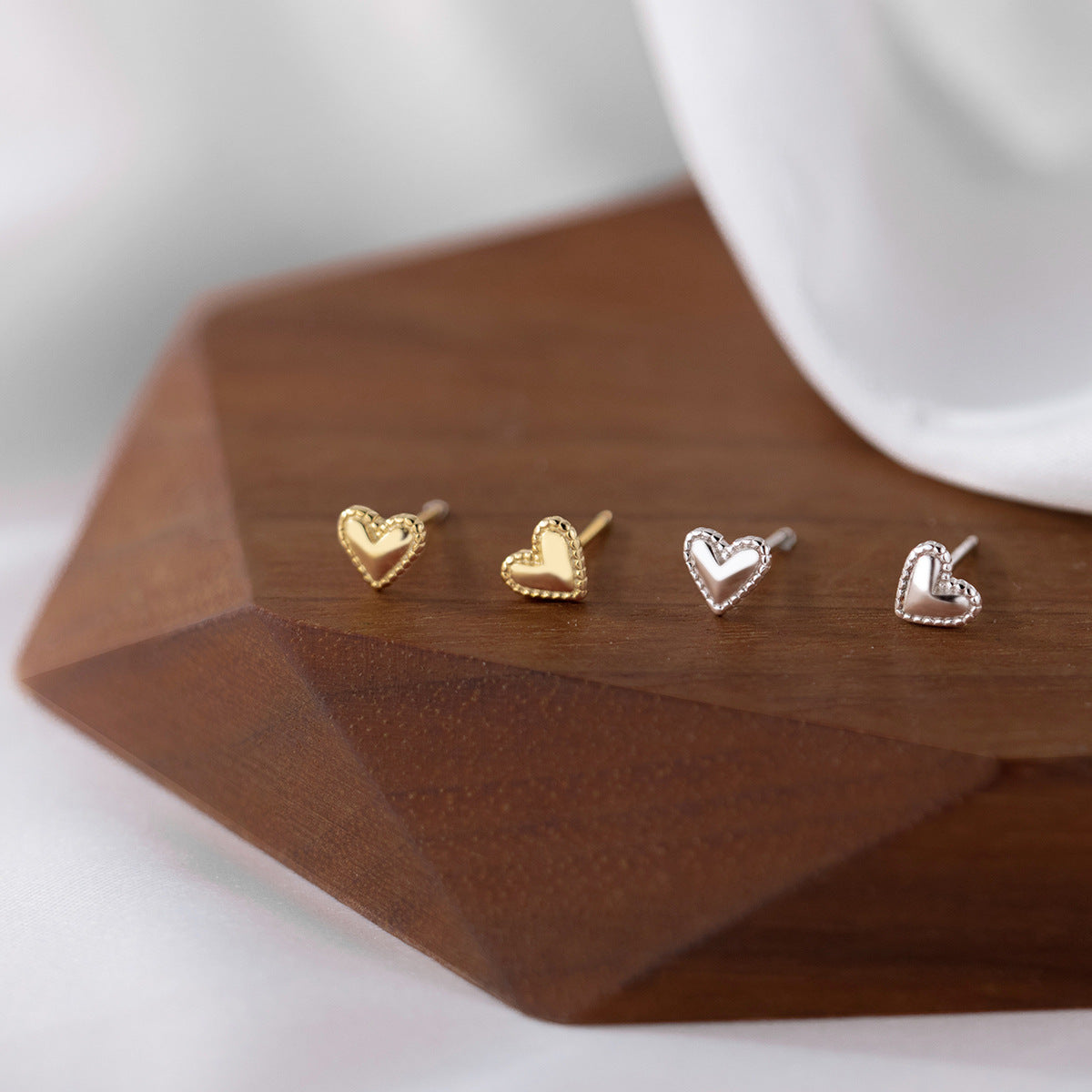 A set of four 925 sterling silver mini heart ear studs, two in a polished silver finish and two in a warm gold finish, displayed on a clean white background.