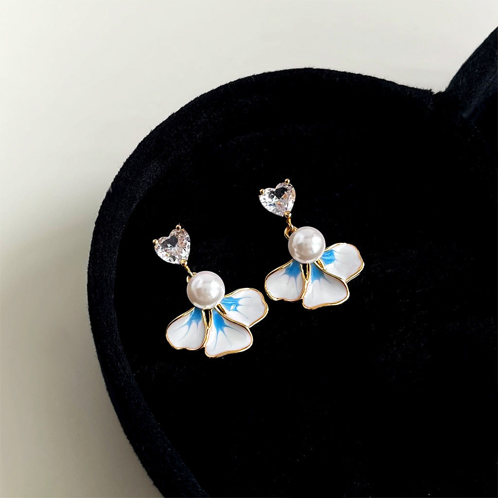 A set of 14k gold plated enamel flower earrings with pearls and heart zircons, elegantly displayed in a black heart-shaped velvet box.