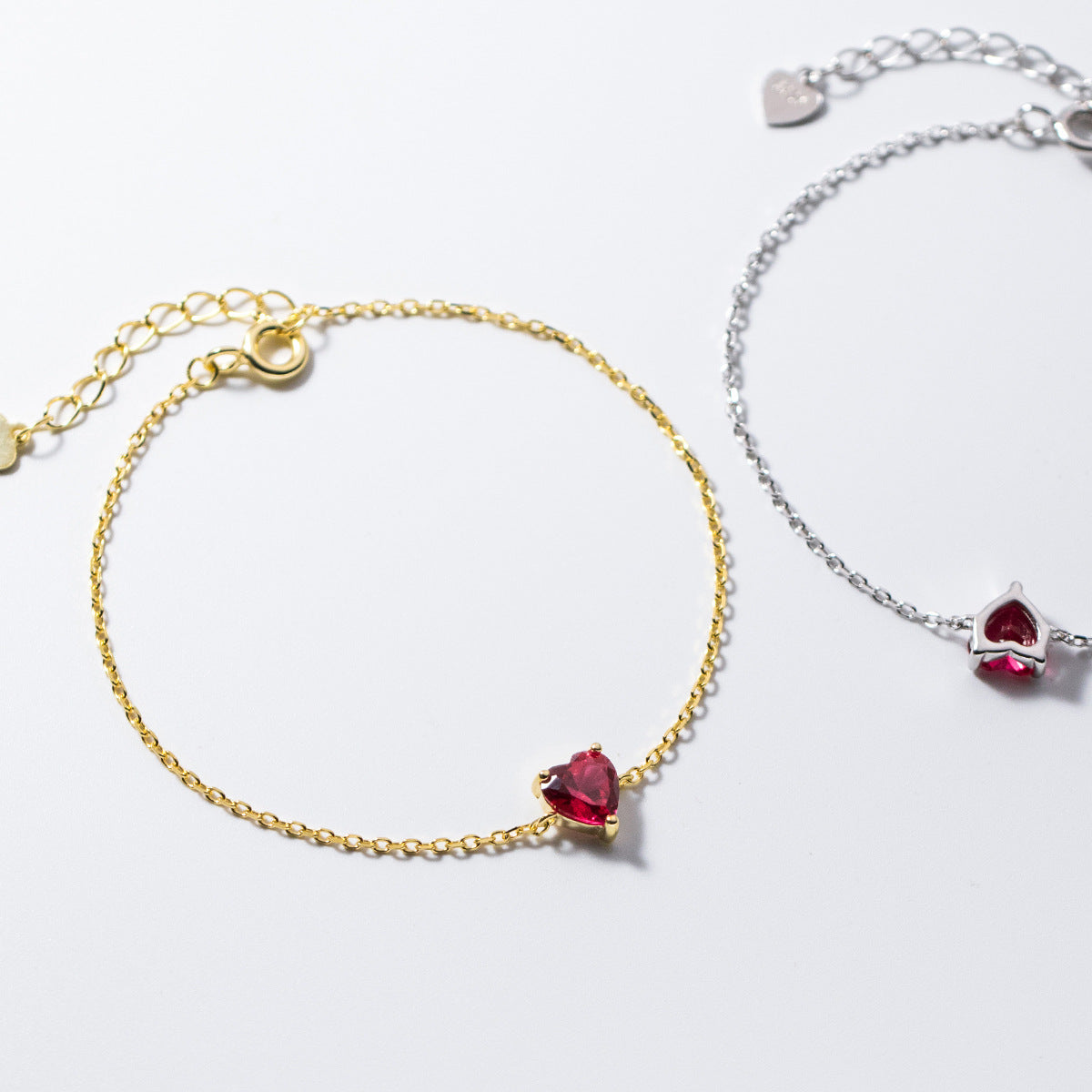 A set of 925 Sterling Silver Minimalist Heart Bracelets, shown in both gold and silver finishes with sparkling red zircon gemstones.