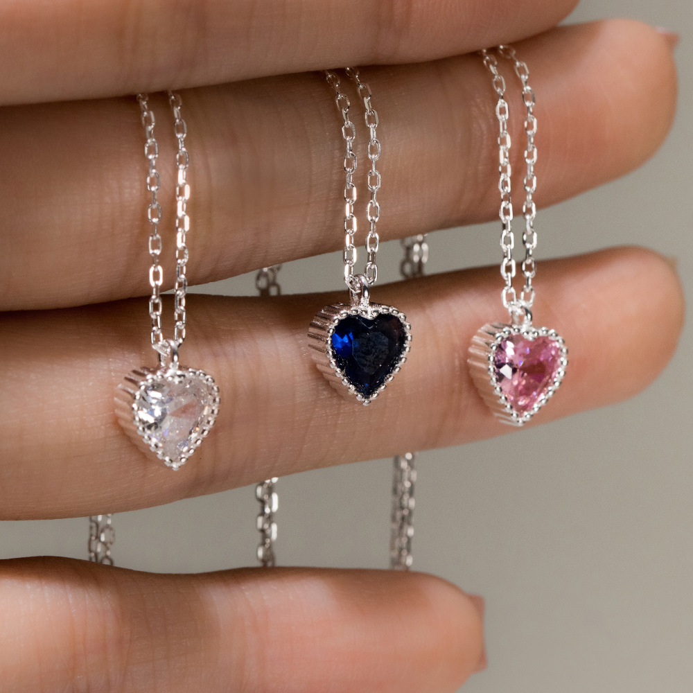 A collection of three 925 sterling silver heart necklaces featuring clear, blue, and pink CZ pave gemstones, displayed on a white background.