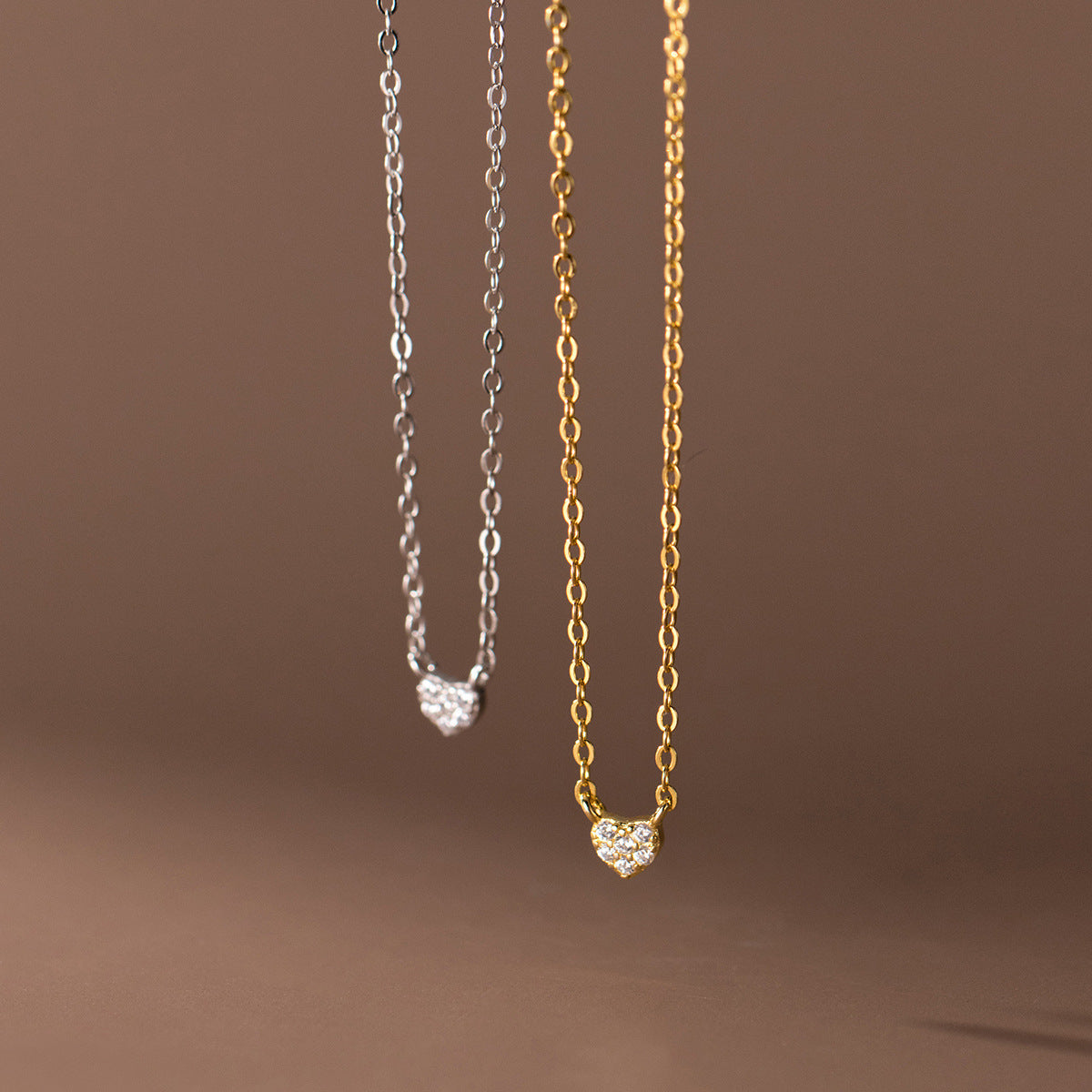 A set of elegant 925 sterling silver heart pendant necklaces, showcasing both the silver and gold options, each adorned with delicate white stones.