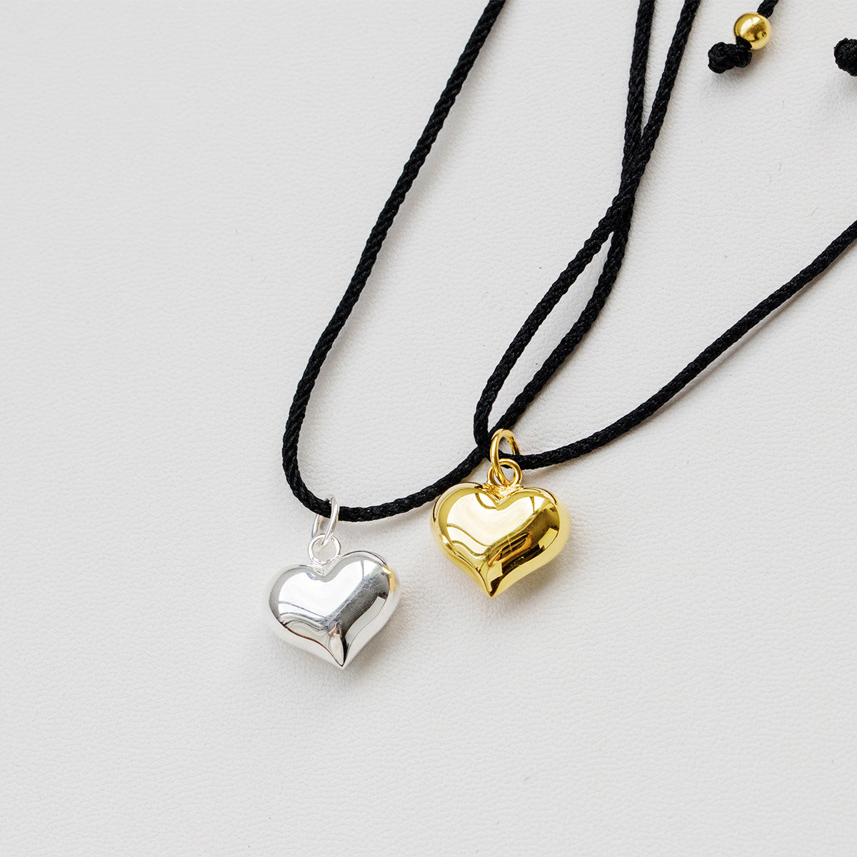 A wholesale set of 925 sterling silver heart pendant necklaces, showing both the silver and gold finish options on black cords.