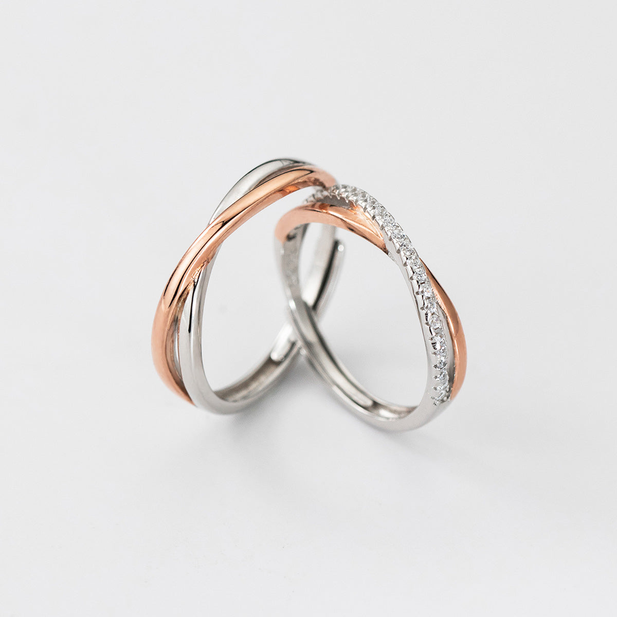 A pair of 925 sterling silver and rose gold Möbius couple rings, intertwined to symbolize unity, with one ring featuring cubic zirconia accents.
