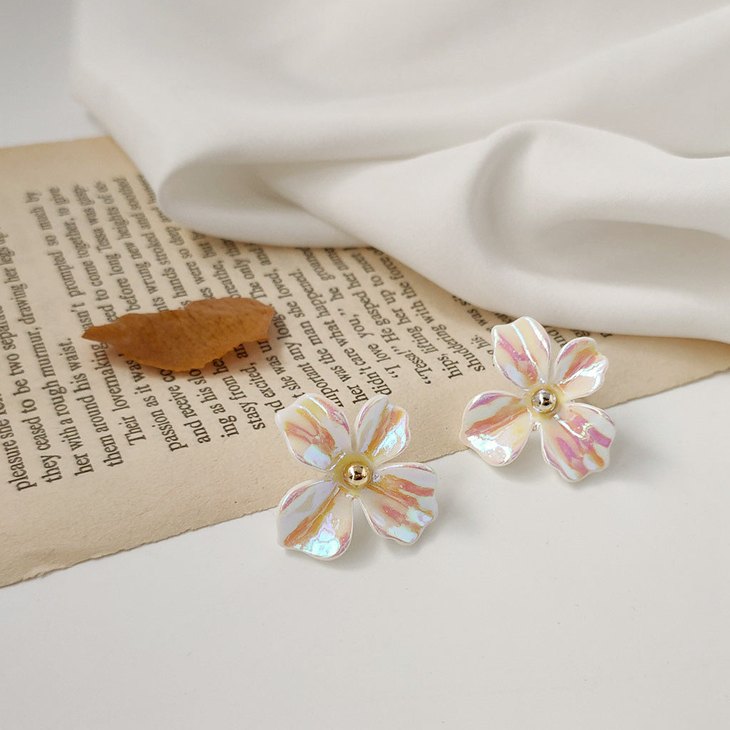 A pair of white flower stud earrings with a beautiful rainbow iridescent effect, made from resin and brass.