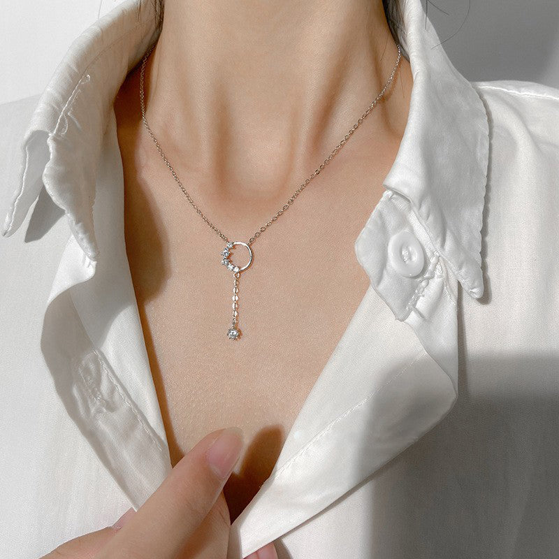 A woman wearing an elegant 925 sterling silver necklace featuring a shiny zircon circle tassel pendant. Part of a set of five.