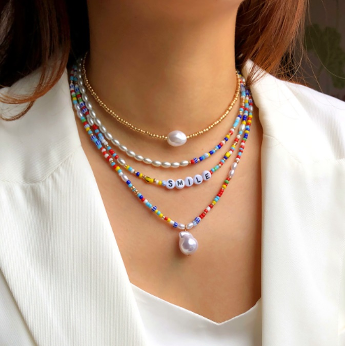 A model showcasing the vibrant Rainbow Handmade Beads Necklace, layered with other colorful pieces to highlight its versatile and cheerful style.