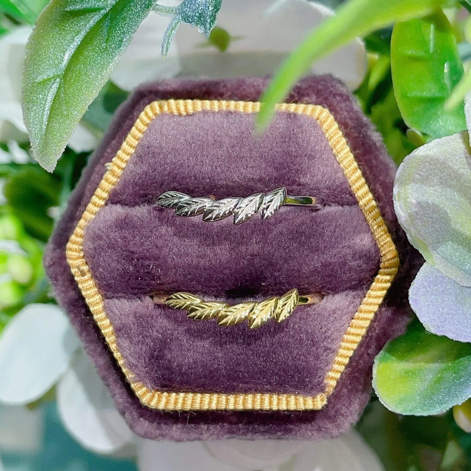 A set of two leaf-shaped 925 sterling silver rings, one in silver and one in gold plating, elegantly displayed in a purple velvet jewelry box.