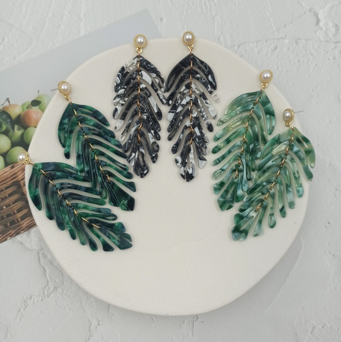 Close-up of Green Leaf Acrylic Earrings showcasing the detailed green and black resin design with gold-tone hardware and a small pearl accent.