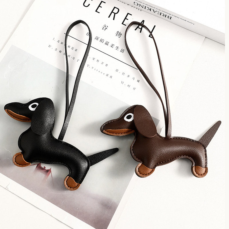 A set of two PU leather dachshund dog bag charms, one black and one brown, displayed side-by-side with their attachment straps.