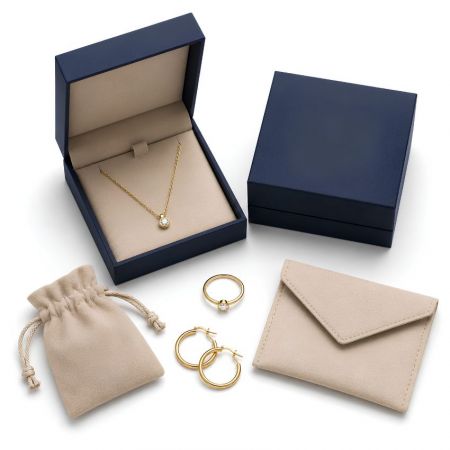 Blue rigid necklace box, beige microfiber drawstring pouch, and envelope bag set displaying gold jewelry.