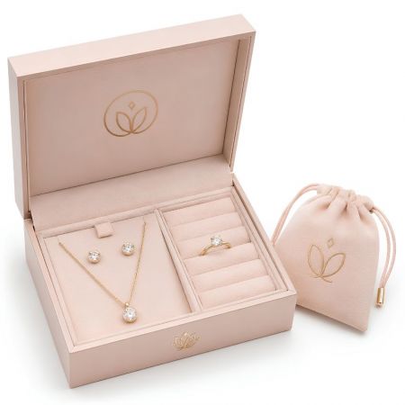 Custom logo jewelry organizer box in pastel pink with a velvet interior, matching drawstring pouch, and gold necklaces.