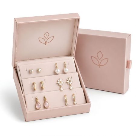 Branded pink cardboard drawer box with a multi-tier velvet earring holder display showcasing gold and pearl drop earrings.