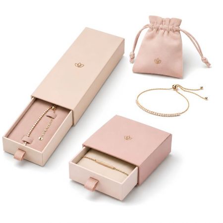 Custom slide-out jewelry boxes for bracelets paired with a pink suede drawstring gift pouch and a diamond tennis bracelet.