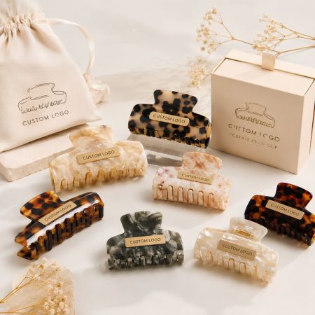 Wholesale cellulose acetate claw clips with gold custom logo plates, private label boxes, and drawstring pouches.