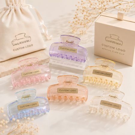 Transparent acrylic claw clips in pastel pink, purple, and blue with custom engraved gold logo plates supply.