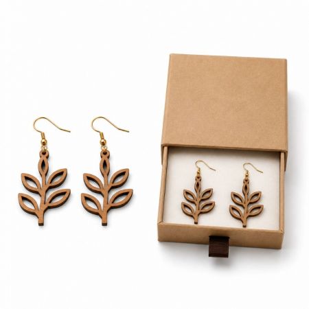 Eco-friendly leaf-patterned wooden drop earrings presented next to custom kraft jewelry packaging box for B2B export.