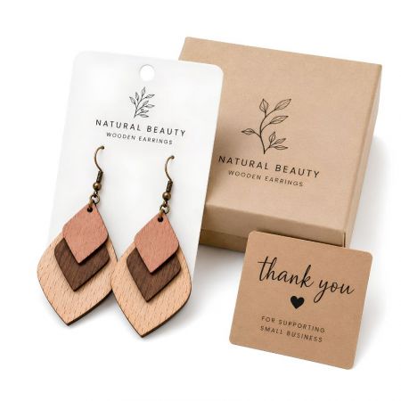 Custom 3-layer geometric wood earrings on a display card next to a kraft paper packaging box and thank you card.