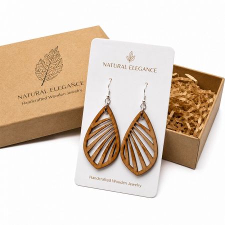 Open-work leaf pattern teardrop wood earrings, presented with a retail cardboard gift box filled with shredded paper.