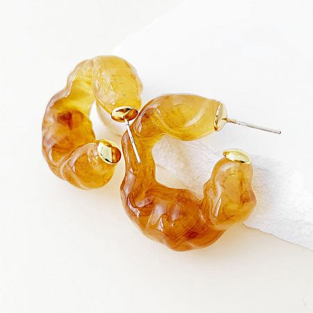 A pair of amber-colored wavy hoop earrings showcasing their unique texture.
