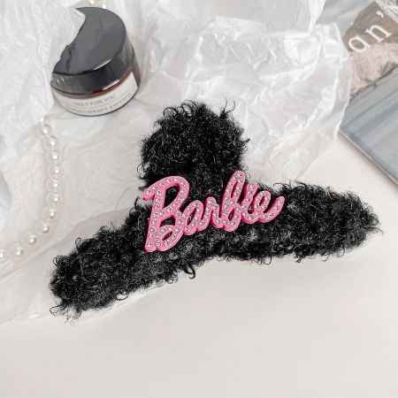 Close-up of a pink plush Barbie-themed hair claw clip with rhinestone details.
