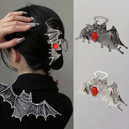 Detailed view of a silver metal bat-shaped hair clip accented with a striking red gemstone.