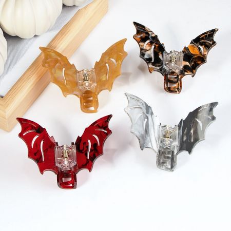 Four bat-shaped hair clips in different colors, including silver, red, and tortoise shell.