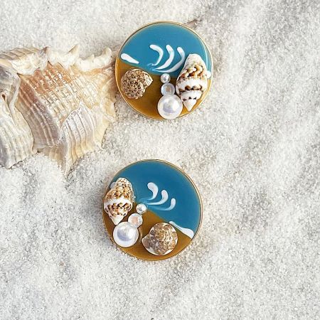 Detailed view of two identical beach-themed earrings with blue enamel and pearl accents.
