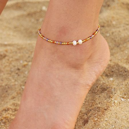 Stainless Steel Beach Jewelry Pearl Stained Glass Beads Anklets Set of 5 - A close-up of a woman's ankle on a sandy beach, wearing a stylish stainless steel anklet adorned with colorful stained glass beads and elegant pearls.