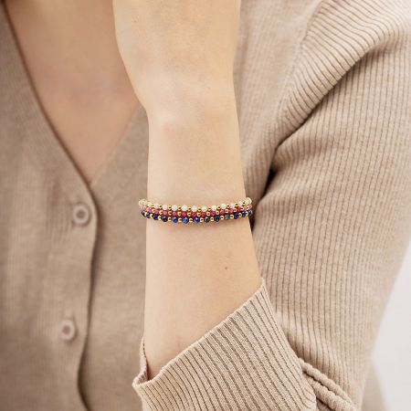A single beaded bracelet with gold chain detail worn on a wrist, showcasing its delicate design.