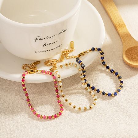Three colorful beaded bracelets elegantly displayed next to a ceramic cup and saucer.