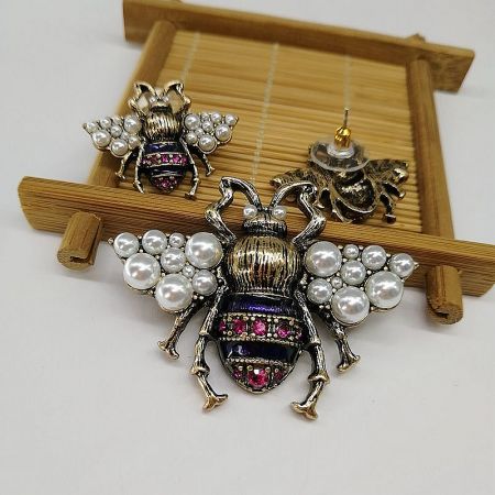 The bee brooch displayed alongside matching earrings, illustrating a complete, elegant jewelry set.