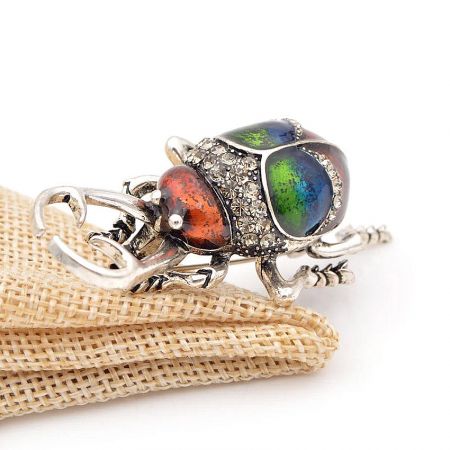 Close-up of the beetle brooch highlighting the three colorful stones on its back.