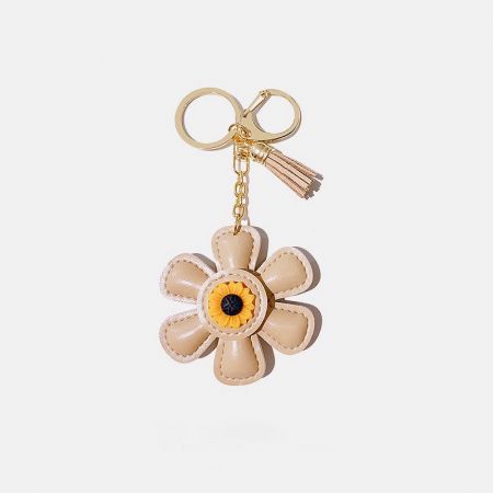 Beige leather sunflower keychain with gold clasp and tassel.