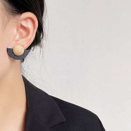 Close-up of a woman wearing the black and natural wood fan-shaped stud earring.