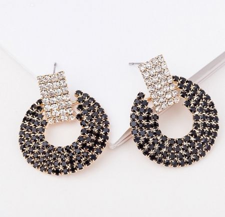 Detailed product shot of the statement earrings, highlighting the intricate arrangement of black and clear rhinestones in a gold setting.