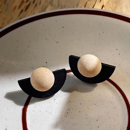 Top-down view of the black and wooden fan-shaped earrings resting on a decorative white plate.