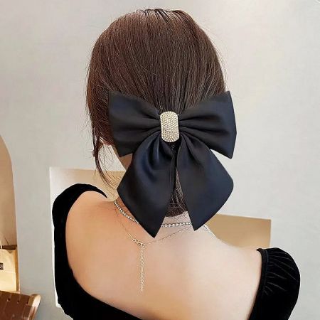 Lifestyle image of the black bow hair accessory worn in a chic, pulled-back hairstyle.
