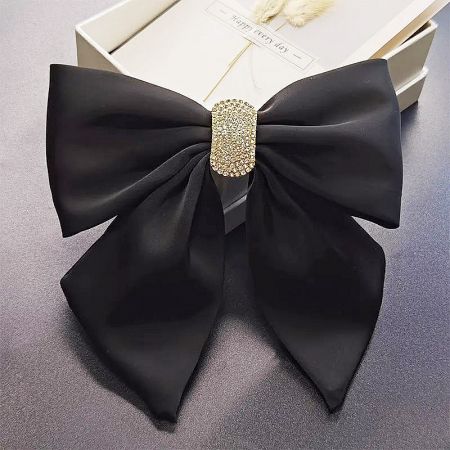 The black bow hair clip with its gold rhinestone clasp, presented in a stylish white gift box.