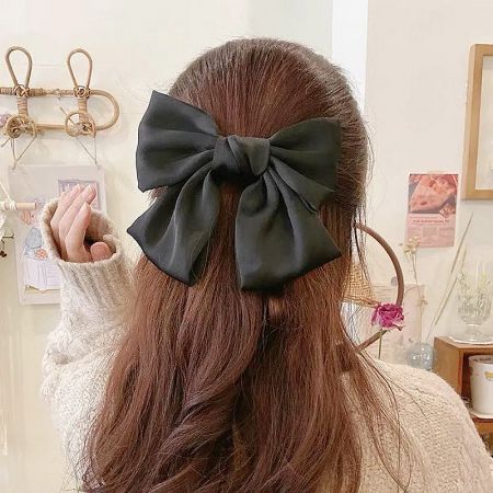 Close-up product shot of a classic black large bow hair clip.