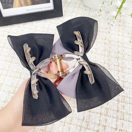 A unique black fabric bow hair clip featuring decorative golden antlers.