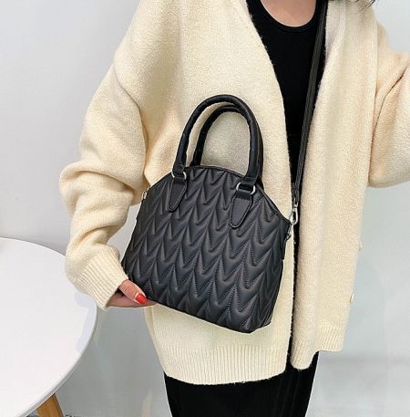 A model holding the black version of the chevron quilted crossbody bag, showcasing its size and style.