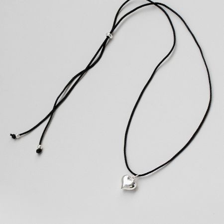 Full view of the black cord necklace with the silver heart pendant.