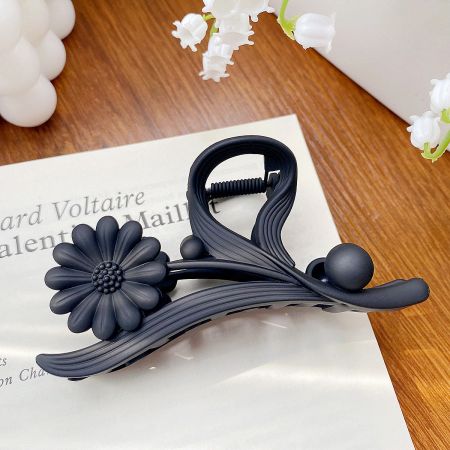 A stylish black daisy flower hair claw clip shown from the side.