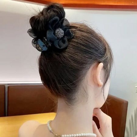 A black mesh flower hair clip styled in a neat hair bun.