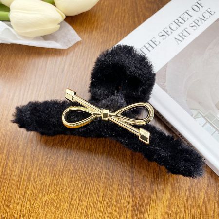 Close-up of the black fluffy hair clip featuring an elegant gold bow detail.