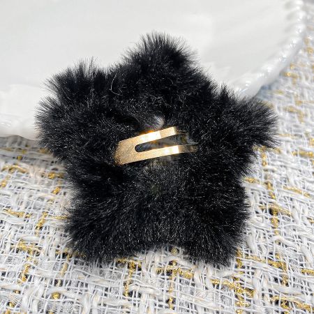 Detailed view of the black plush star hair clip, highlighting the gold metal snap clip mechanism.