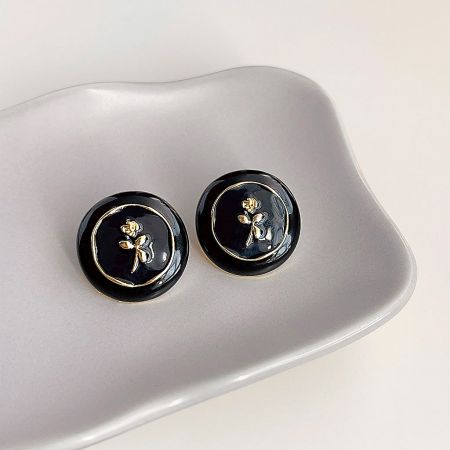 A pair of black enamel stud earrings from the set, featuring a detailed gold bee design.