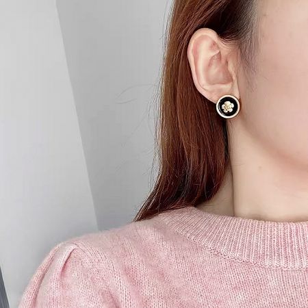 Model showcasing the elegant black and gold floral earring for size and style reference.