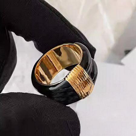 Close-up of a single black vintage enamel ring with intricate gold-plated details.